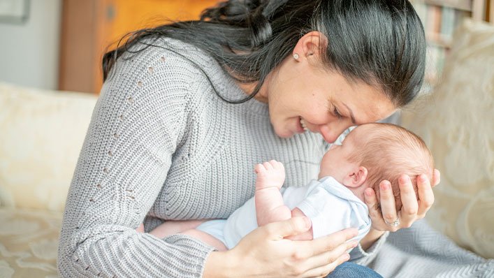 Lady cuddling her baby and smiling