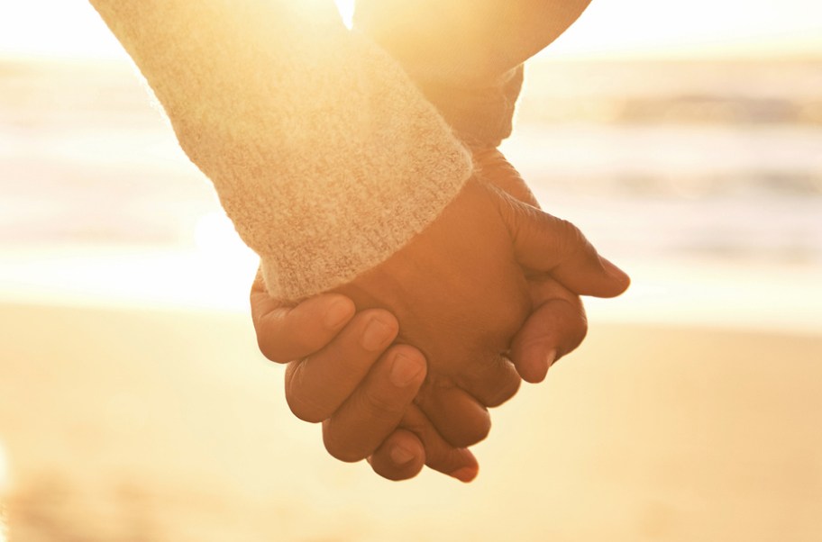 Couple holding hands on a beach at sunset