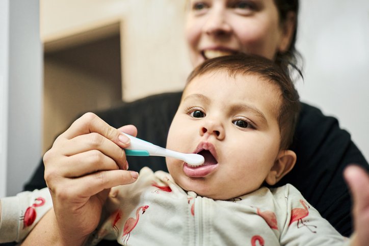 Parent brushing their baby's teeth