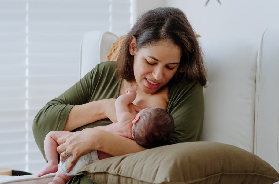 Mother breastfeeding her baby while sitting in an armchair