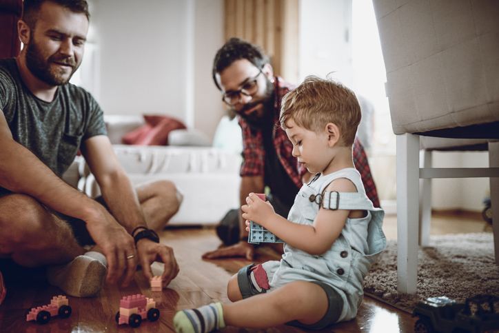 Two parents playing with building blocks with their toddler
