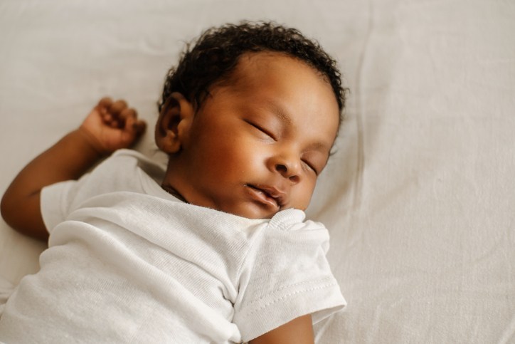 Baby sleeping on their back on a bed