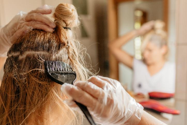 Woman applying hair dye at home
